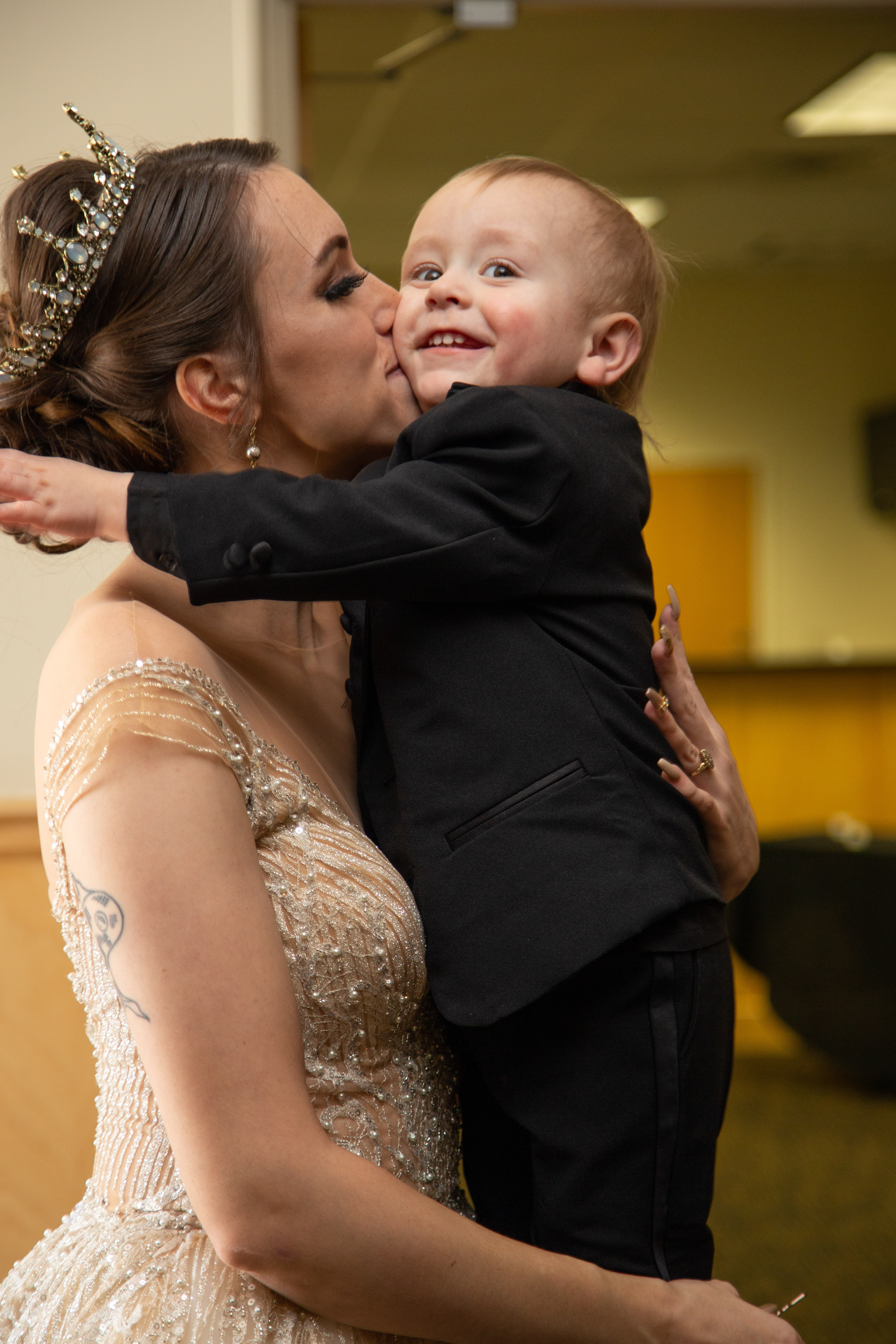 Caitlyn kissing a little one in a tuxedo — a joyful wedding moment