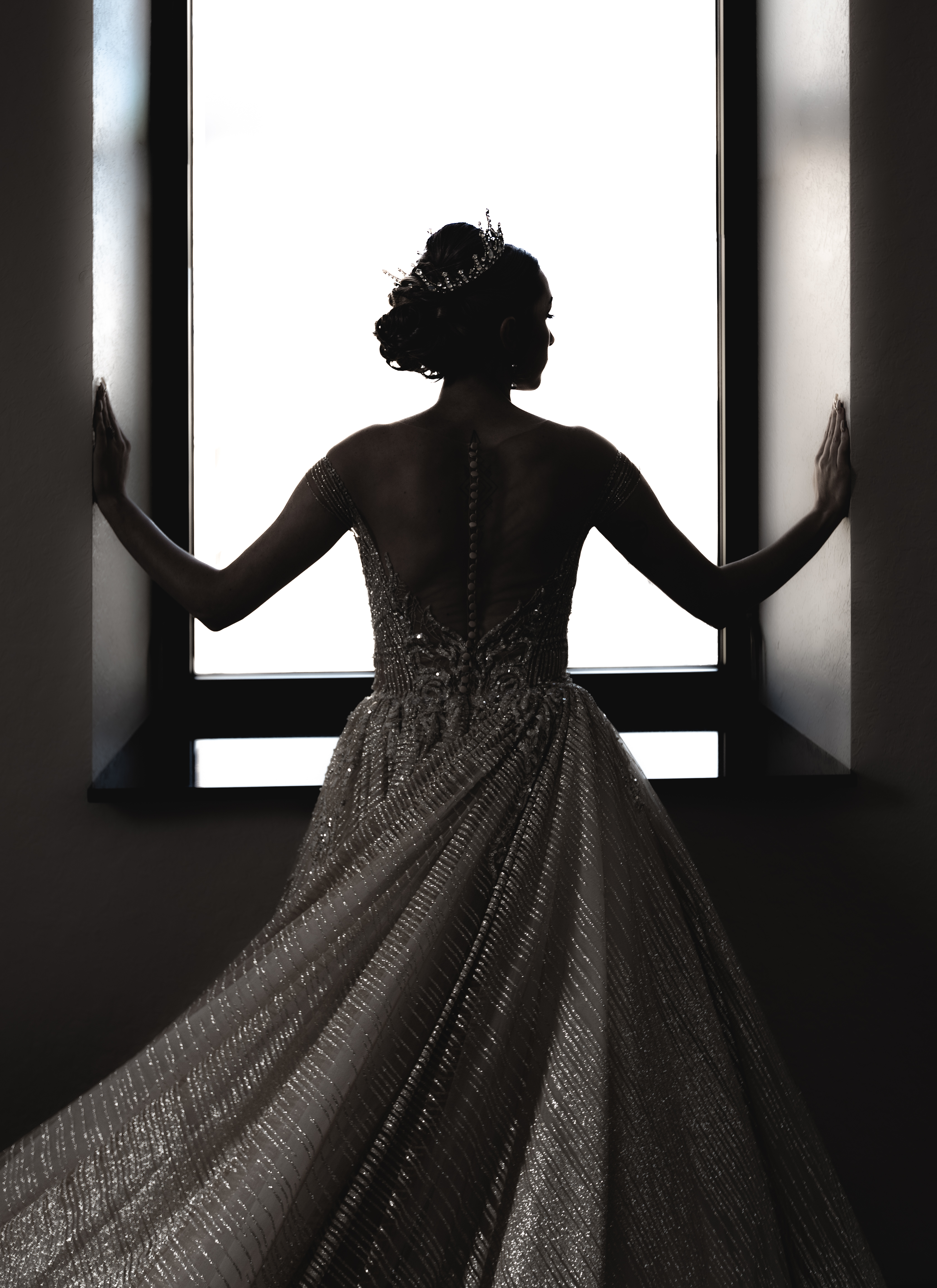 Caitlyn silhouetted in her gown at the window